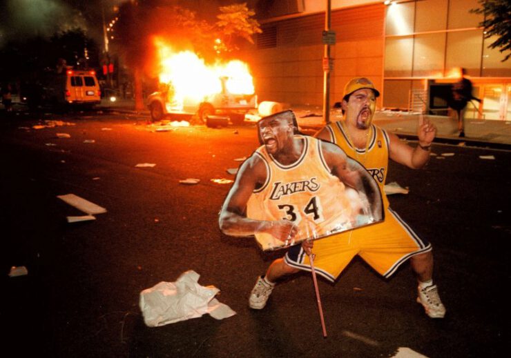 A Lakers fan celebrating in front of a burning
car.